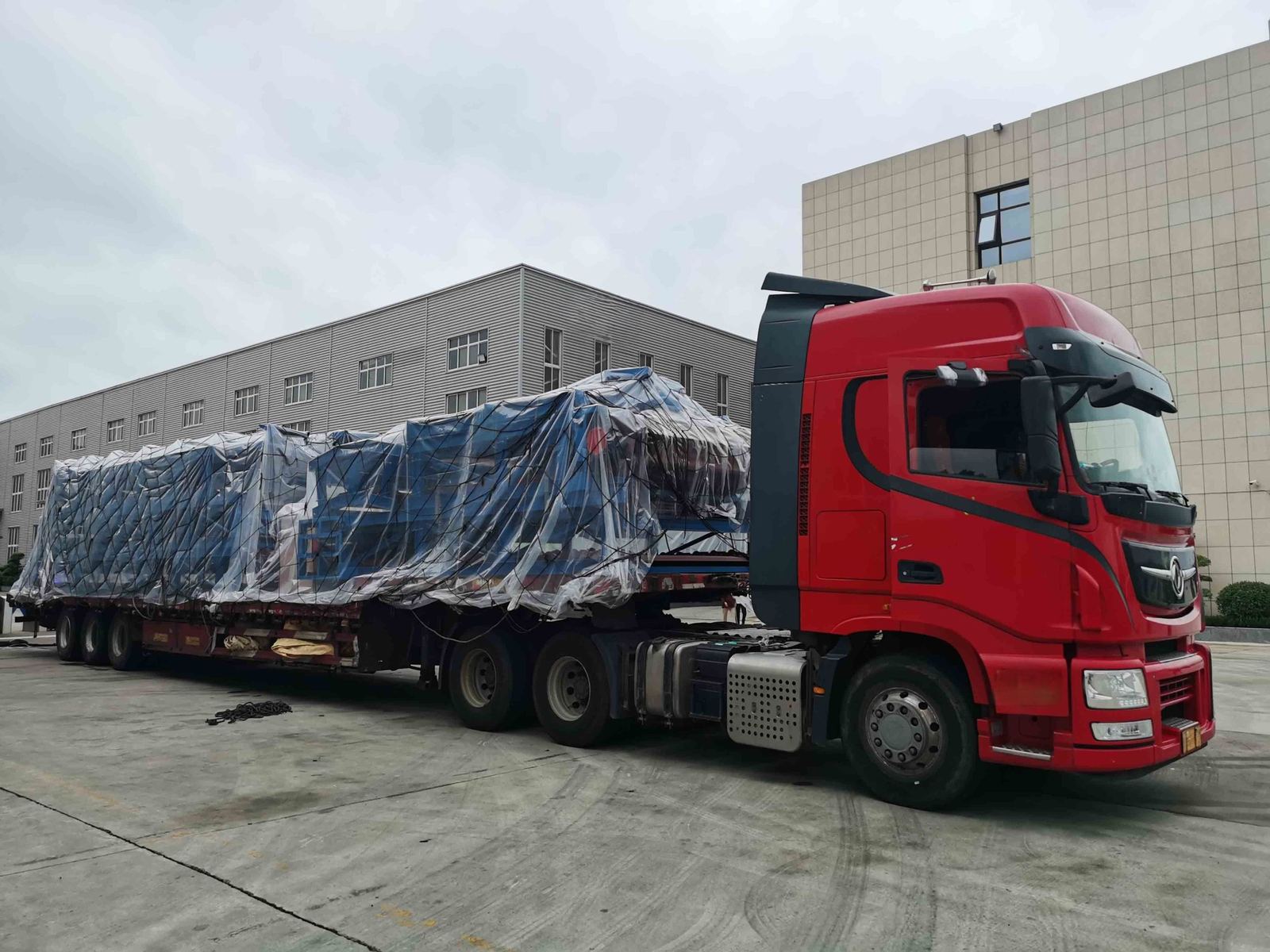 Prime mover with a flatbed trailer carrying wrapped machinery